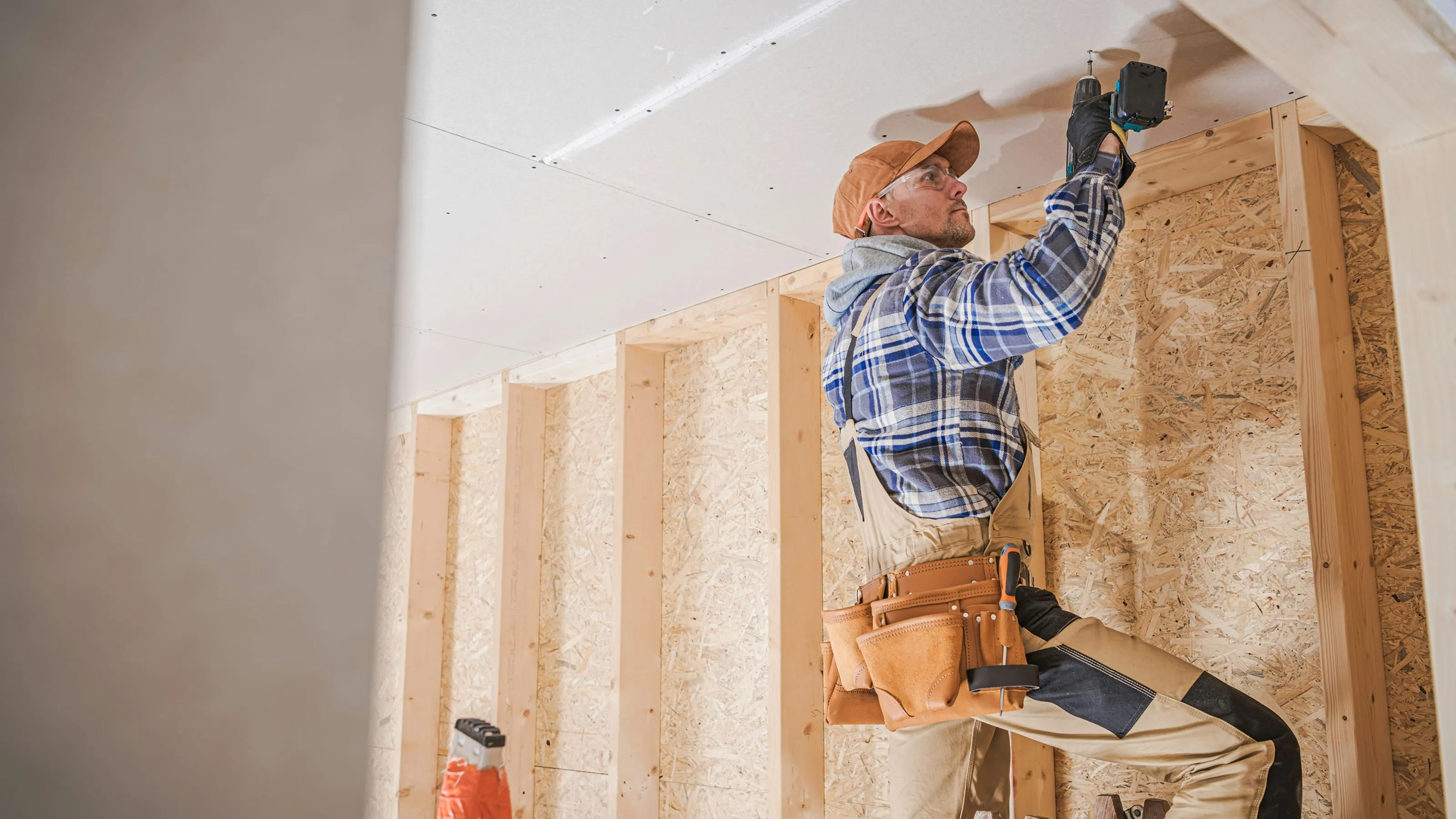 Carpenter fastening interior framing on a residential construction site.