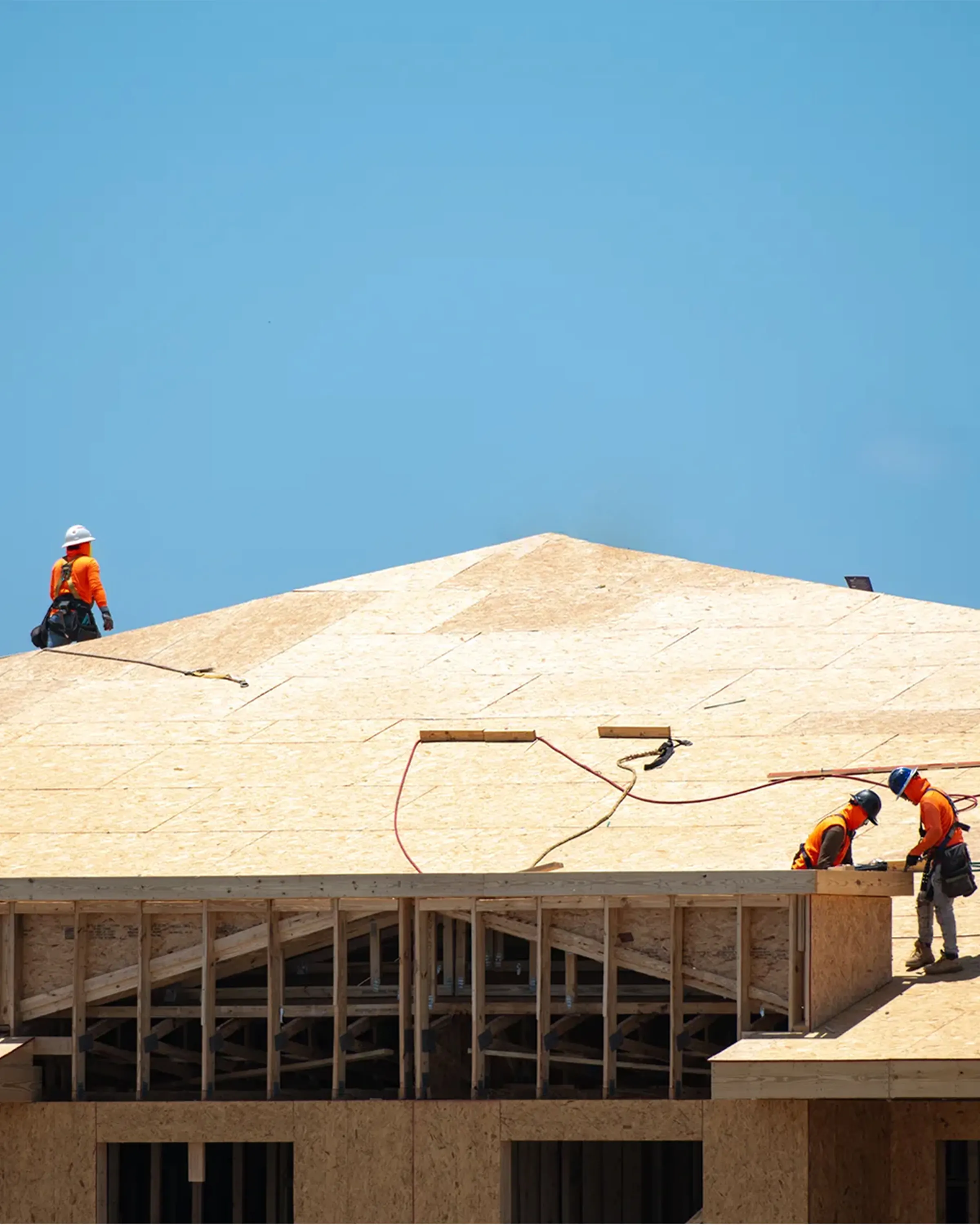 Construction and Roofing Contractors working on the roof of a new building on a sunny day